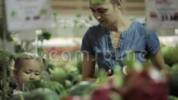 年轻的母亲和小女儿在超市挑选水果视频的预览图