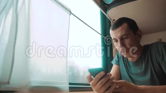 人旅行写智能手机信息社交媒体在信使坐在火车旁的窗口旅行者概念视频的预览图