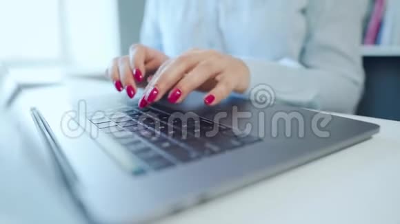 在笔记本电脑键盘上输入漂亮指甲的女性手视频的预览图