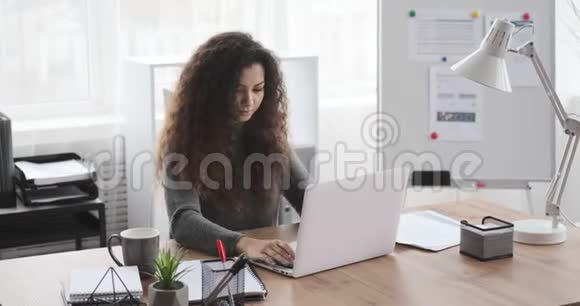 女商人在办公室的笔记本电脑上打字视频的预览图