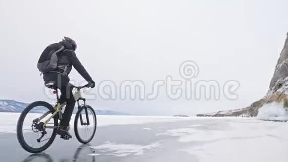 人正骑自行车在冰窟附近有冰洞和冰柱的岩石非常美丽骑自行车的人穿着视频的预览图