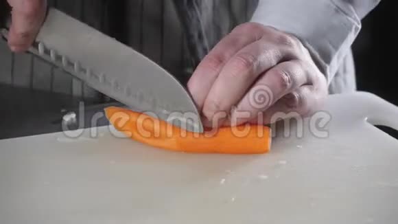 用刀切新鲜蔬菜的手特写年轻的厨师在白色的切割板特写上切胡萝卜烹饪视频的预览图