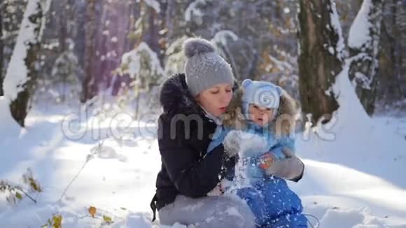 阳光明媚的一天一个女孩带着一个孩子在公园里玩雪视频的预览图