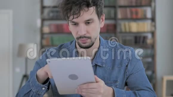 休闲青年男子在平板电脑上浏览互联网视频的预览图