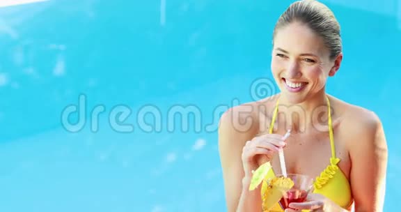穿着比基尼的金发美女在泳池边享受鸡尾酒视频的预览图