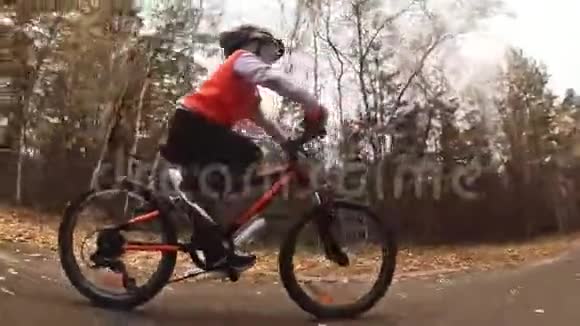 一个高加索儿童在秋季公园骑自行车小女孩骑着黑色橙色的自行车在森林里孩子是干的视频的预览图