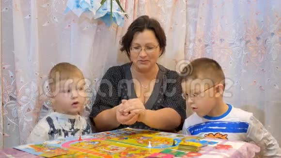 孩子们和家人在桌上玩棋盘游戏视频的预览图
