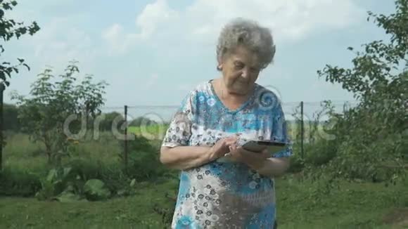 80多岁的老妇人在户外手持数码平板电脑视频的预览图