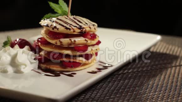 放在桌子上的盘子上装饰着草莓的一部分煎饼的照片镜头在桌子上旋转视频的预览图