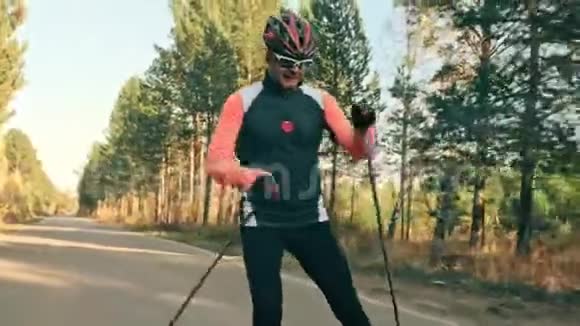 训练运动员滑旱冰双项全能骑在带有滑雪杆的溜冰鞋上戴在头盔上秋天视频的预览图