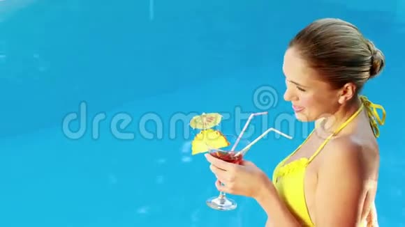 穿着比基尼的金发美女在泳池边享受鸡尾酒视频的预览图
