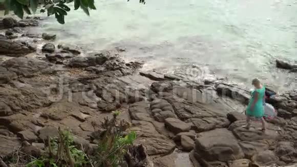 在岩石海滩上散步的年轻女子视频的预览图