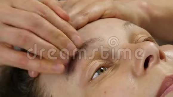 在水疗中心接受头部按摩的女人做面部按摩的女医生4K视频的预览图
