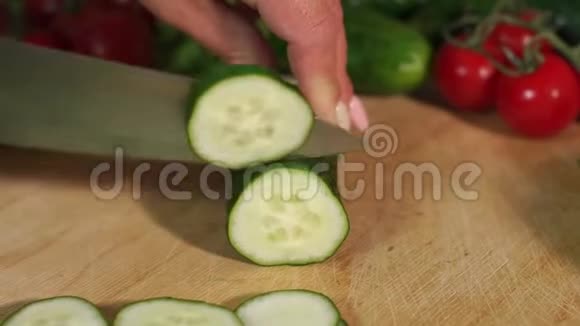 一个女人在木切板上切新鲜黄瓜的特写镜头视频的预览图