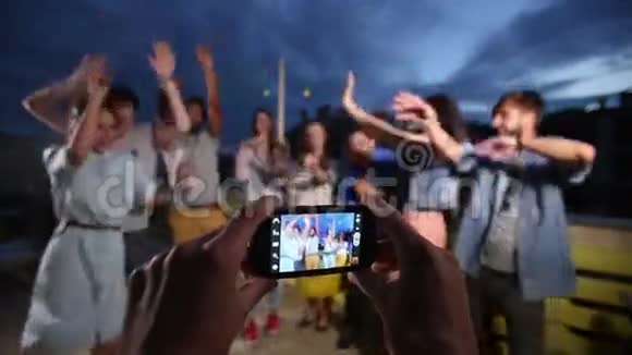 手握电话拍摄快乐的朋友群跳舞视频的预览图