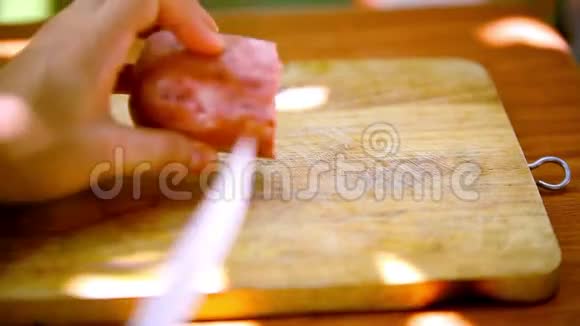 女性的手在木切上切香肠视频的预览图