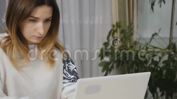 坐在桌子旁的年轻漂亮的女性在笔记本电脑上打字视频的预览图