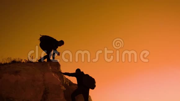 两个男子协同游客爬上一座山徒步旅行者徒步旅行冒险登山日落攀登视频的预览图