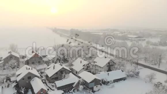无人机4K空中镜头村庄在平原覆盖着雪白色多云的冬季天气视频的预览图
