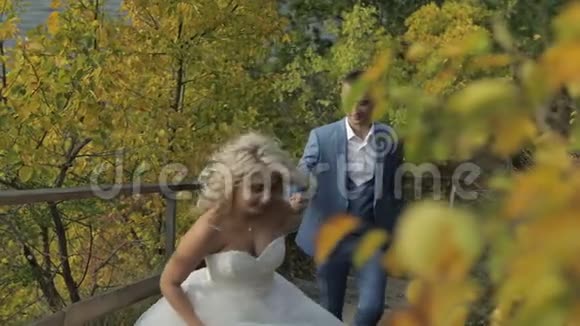 年轻漂亮的新婚夫妇一起在河边的公园里可爱的新郎和新娘结婚纪念日慢动作视频的预览图