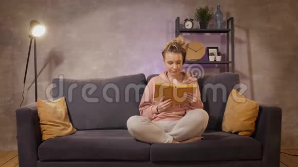 一个年轻的女人坐在沙发上看书视频的预览图