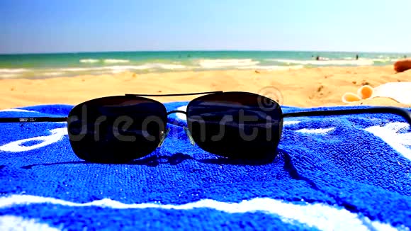 沙滩上的太阳镜和蓝色毛巾视频的预览图