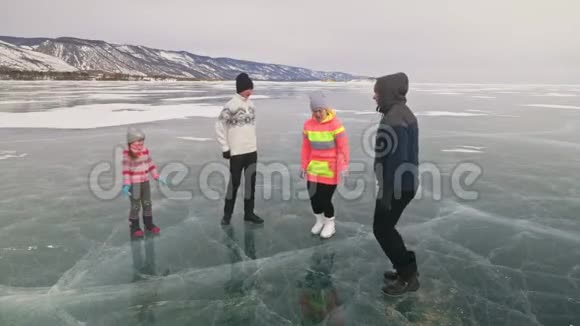 家庭在大自然中冰上做运动父亲在冬天训练他的家人母女和儿子看着他视频的预览图