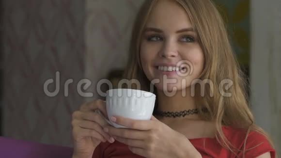 漂亮的年轻女人家里坐在扶手椅上喝茶视频的预览图