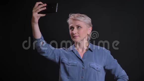 有魅力的高加索女人在电话中微笑着摆姿势自拍的特写照片视频的预览图