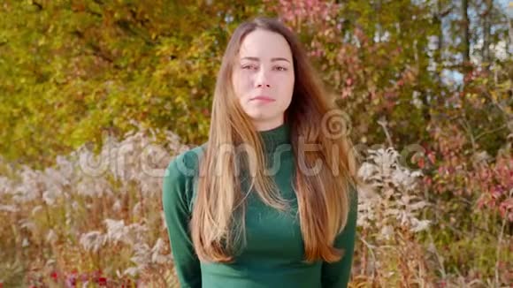 秋天黄树背景下一位年轻迷人的黑发女子的肖像视频的预览图