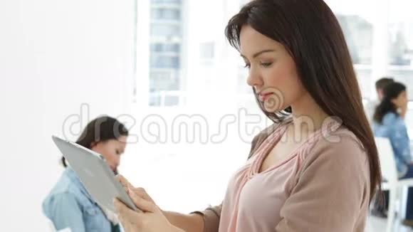 有创意的女商人使用平板电脑背后的同事视频的预览图