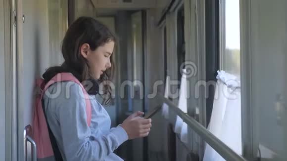 小女孩带着背包和智能手机在火车车厢里散步旅行交通方式铁路视频的预览图