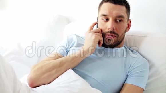 男人在家里的床上打智能手机视频的预览图