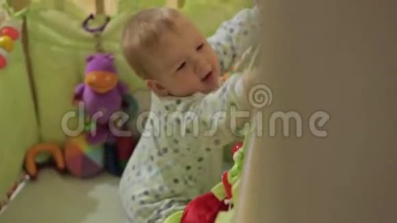 可爱的小男孩站在婴儿床上视频的预览图