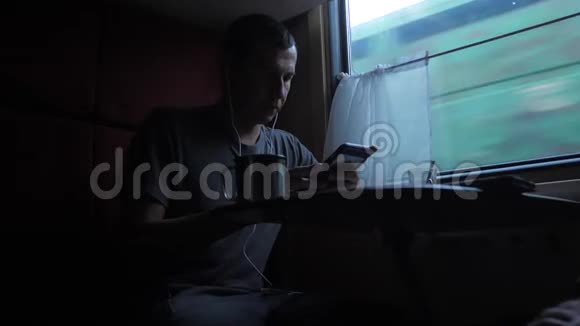 男人剪影坐在火车车厢里手里拿着智能手机喝着咖啡和茶慢动作视频的预览图