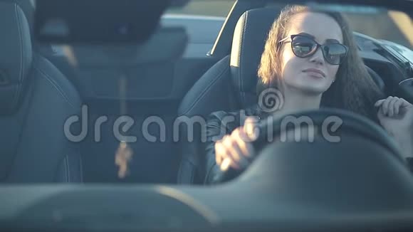 穿着皮夹克的长发戴着墨镜的皮裤的漂亮女孩坐在驾驶室里视频的预览图
