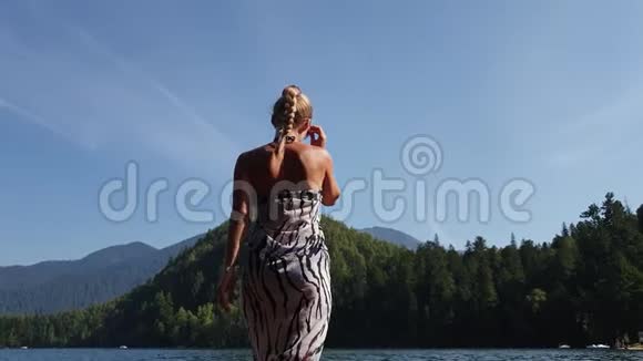 女人戴着太阳镜和一条薄纱披肩在码头上水上行走女孩在洪水木水下码头休息人行道视频的预览图