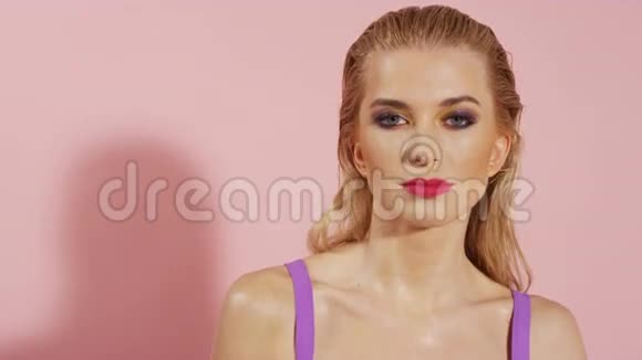 美丽的年轻开朗的女人在粉红色的背景穿着粉红色的背景视频的预览图