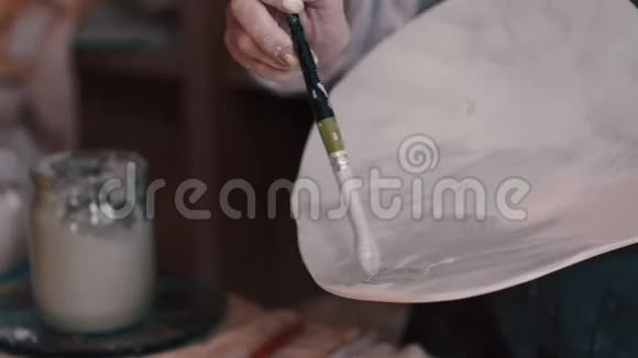 专业的陶工在她在窑里烤过一道菜后装饰和绘画视频的预览图