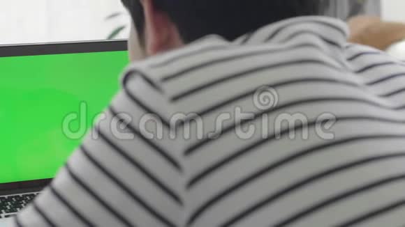 拍过肩膀的亚洲男孩看着绿色的屏幕视频的预览图