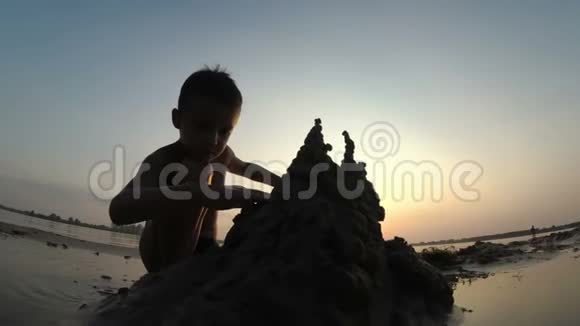 海滩儿童剪影在日落时建造沙堡视频的预览图