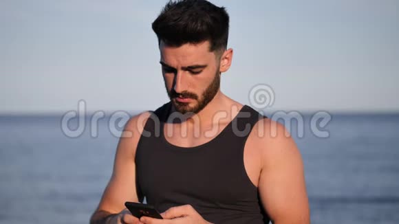 海边的运动员用手机输入信息视频的预览图