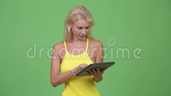 年轻快乐的金发美女使用数码平板电脑思考视频的预览图