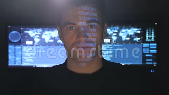 在一个充满监控屏幕的数据中心特写英俊的黑客程序员的画像视频的预览图