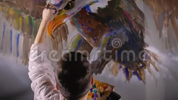 艺术家设计师在墙上画一只鹰工匠装饰师用丙烯酸油彩画一幅画视频的预览图