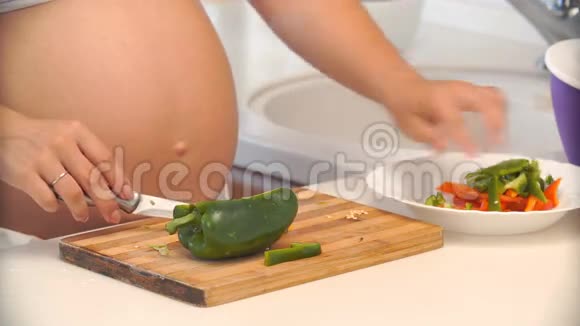 孕妇在厨房里切胡椒蔬菜沙拉视频的预览图