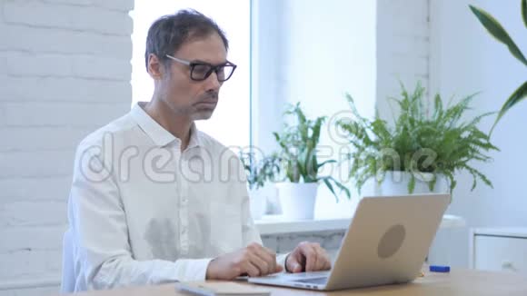 中年男子在办公室用笔记本电脑工作关门视频的预览图