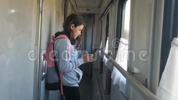 小女孩走在火车车厢里带着背包的生活方式和智能手机旅游运输铁路视频的预览图