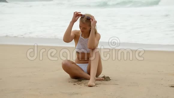 美丽的女人在海边为照相机摆姿势视频的预览图
