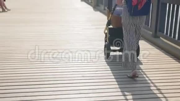 妈妈带着婴儿车在长廊散步家庭母性和人的概念有婴儿的幸福母亲视频的预览图